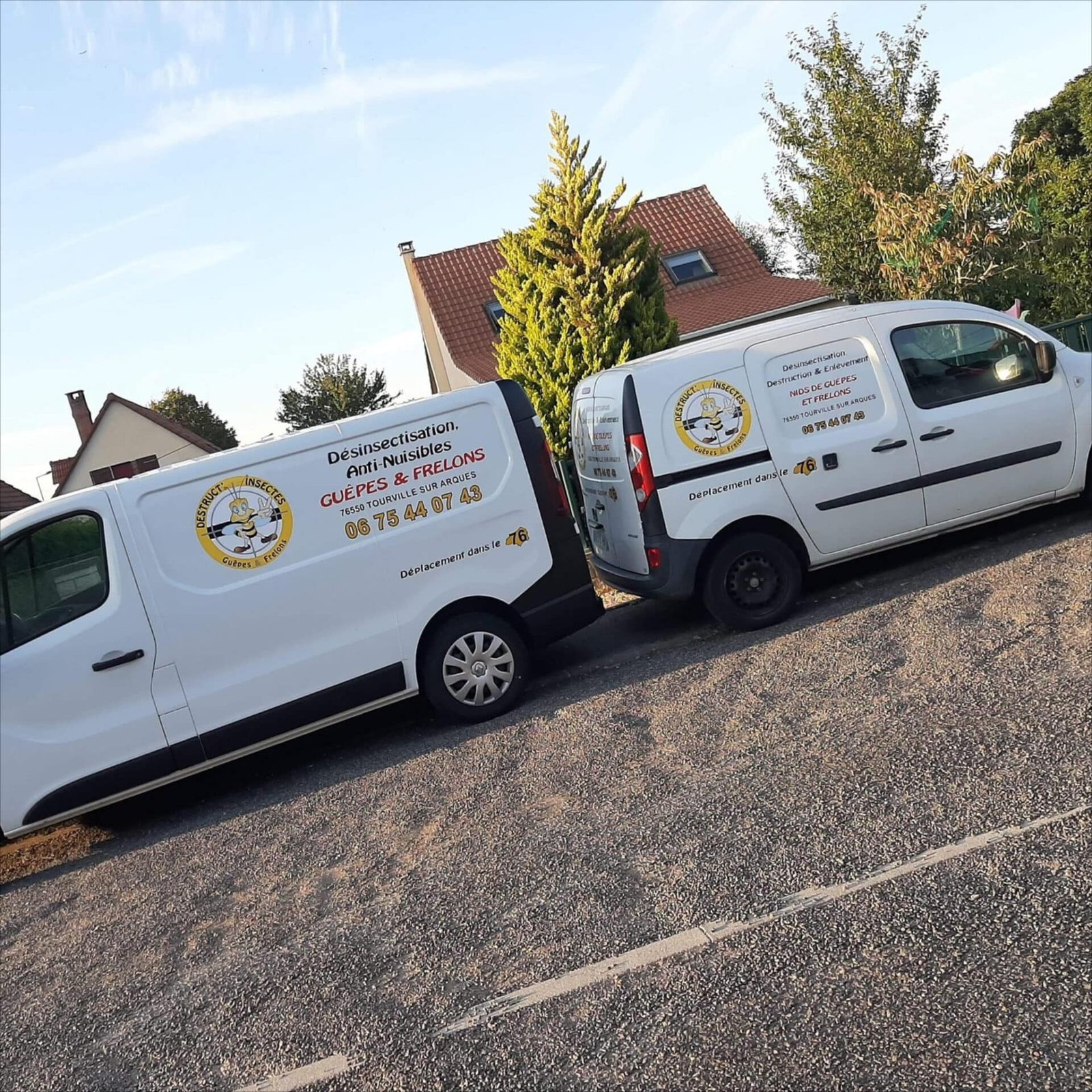 Deux fourgonnettes blanches garées côte à côte devant une maison portant le logo de la société Destruct Insectes
